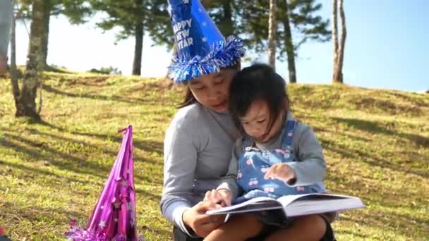 Aziatische Moeder Die Een Boek Voorleest Aan Haar Dochter Voorjaarstuin — Stockvideo