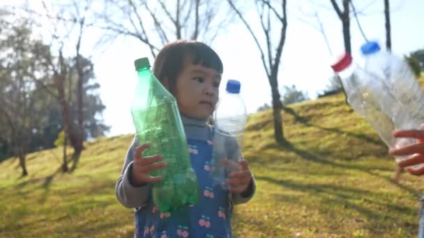 小さな子供の女の子のボランティアは リサイクルのためのビニール袋に公園内のプラスチック製の水ボトルを収集します 環境の保全と廃棄物の削減 — ストック動画