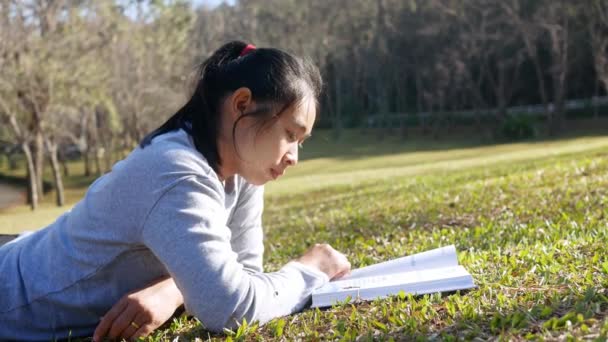 Asiático Relaxado Jovem Mulher Deitado Campo Grama Para Ler Livro — Vídeo de Stock