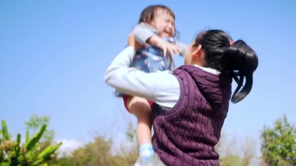 Asian Mother Lifting Playing Her Daughter Holiday Garden — Stockvideo