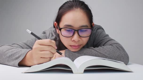 眼鏡をかけた若い女性が図書館で本を読みながら線を引いて要約を書きます — ストック動画