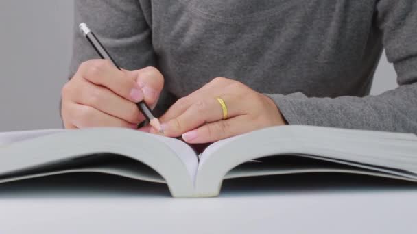 図書館で本を読んでいる間に 女性の手を閉じて線を引くと短い要約を書く — ストック動画