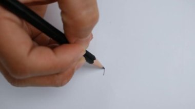 Sanatçının elleri kağıda siyah kalemle düz bir çizgi çiziyor..