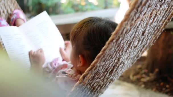 Милая Маленькая Девочка Расслабляется Читает Книгу Лежащую Гамаке Открытом Воздухе — стоковое видео