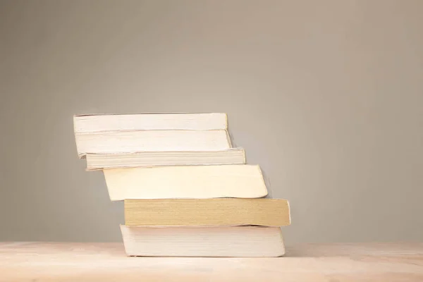 Uma pilha de livros velhos descansando em uma mesa empoeirada no quarto . — Fotografia de Stock