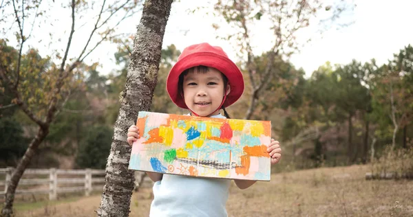 Niña feliz mostrando su trabajo para colorear en cartón en el — Foto de Stock