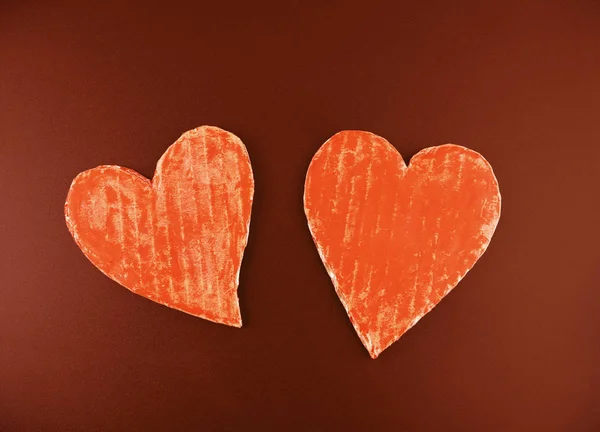Two heart-shaped recycled cardboard isolated on a red background