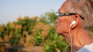 Asyalı son sınıf öğrencisi sağlık için parkta koşuyor ve kulaklıkla müzik dinliyor. Sağlık hizmetleri kavramı.