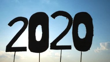 Mukavvanın silueti mavi gökyüzü arkaplanı üzerinde 2020 numaraya geri dönüşür ve yazı boyunca güneş parlar. Yeni Yıl ve Kutlama Kavramları.