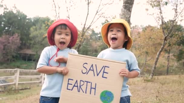 Gezegeni Kurtarın Posterini Tutan Iki Küçük Kız Kardeş Ormanda Plastik — Stok video