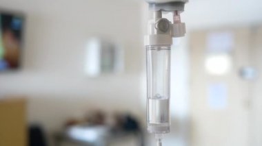 Hastanedeki bulanık lüks Vip odası arka planında hasta ve infüzyon pompası için tuzlu solüsyon damlası yakın plan..