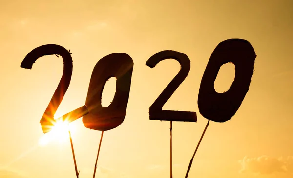 Silhouette of recycle cardboard into 2020 numbers over sunset sk — Stock Photo, Image