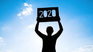 Elinde 2020 yazısıyla geri dönüşüm kartonu tutan bir kadın silueti mavi gökyüzü arkaplanı ve metinde gün ışığı. Yeni Yıl ve Kutlama Kavramları.