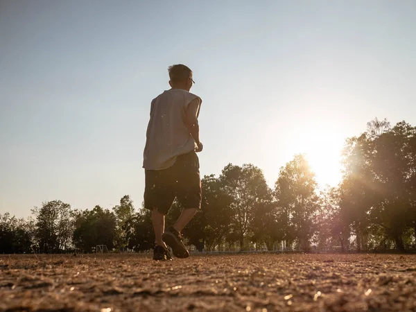 Asijské senior muž jogging v parku přes západ slunce nebe pozadí. — Stock fotografie