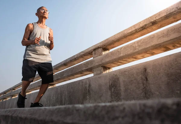 Spor giyimli Asyalı son sınıf öğrencisi gökyüzü sırtında köprüde koşuyor. — Stok fotoğraf