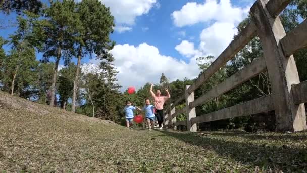 春の庭で一緒にハート型の赤い風船で走るのが楽しいアジアの家族 幸せな家庭と子供時代の概念 — ストック動画