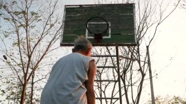 Asyalı yaşlı adamlar yaz günü oyun alanında basketbol oynuyorlar. Sağlıklı yaşam tarzı ve sağlık hizmeti kavramı.