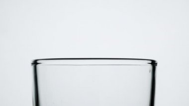 Yeşil şişeden beyaz arka planda izole edilmiş meyve suyunu cama dök..