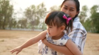 Mutlu Asyalı anne ve küçük kızı yaz parkında birlikte oynuyorlar. Mutlu aile ve çocukluk kavramı.