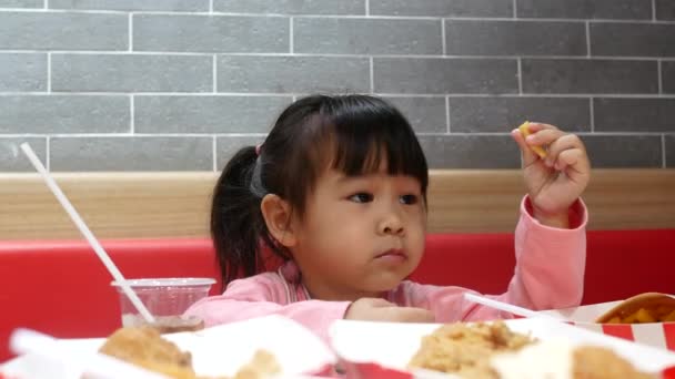 アジアの兄弟姉妹は 家族と一緒にサービスショップでフライドチキン フライドポテト 蜜を食べて楽しんでいます Kfcは世界的に有名なアメリカのファーストフードレストランです 健康コンセプト — ストック動画