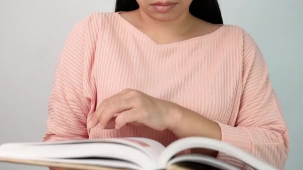 若い女性が本のページをめくり 図書館で読んでいる間にページに沿って指を動かす 選択的焦点 — ストック動画
