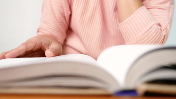 若い女性が本のページをめくり 図書館で読んでいる間にページに沿って指を動かす 選択的焦点 — ストック動画