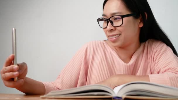 Азиатская Молодая Женщина Помощью Смартфона Сидит Гостиной Расслабляясь Чтения Книг — стоковое видео