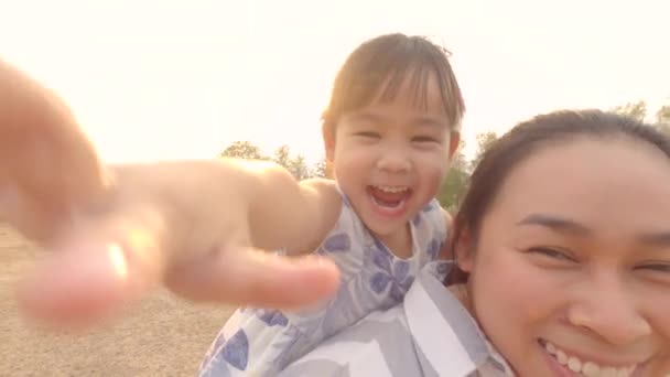 快乐的小女孩坐在妈妈的背上跑在公园里 幸福家庭和童年的概念 — 图库视频影像
