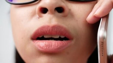 Makyajsız kadın dudaklarının portresini kapat ve cep telefonunda öfkeyle konuşan gözlük tak ve kaşlarını çatma, dudaklara odaklan..