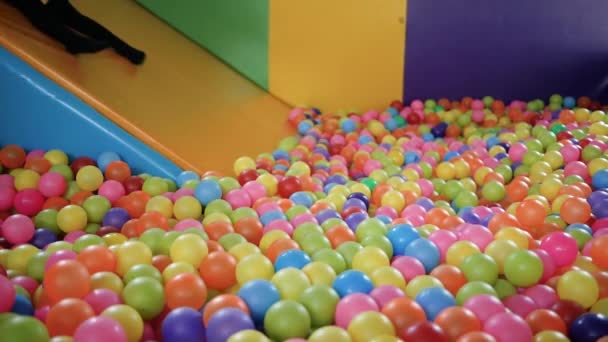 カラフルなボールでプラスチック製のドライプールでスライドをプレイする楽しみを持っているかわいい子供の女の子子供たちの遊び場の屋内 — ストック動画