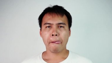 Hasta Asyalı adamın portresi, ağzı kuruduğu için gri arka planda yalanıyor. Grip belirtileri gösteren bir erkek..