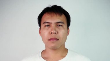 Ciddi Asyalı bir adamın portresi gözlerini kapar ve gri arka plan yüzünden gerildiğini belirterek kafasını ovuşturur. Duygu ve ifade kavramları.