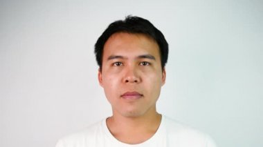 Heyecanlı Asyalı mutlu adamın yakın portresi beyaz tişört giyer ve bir spor maçında zafer ya da iş yerinde başarı göstergesi olarak bir jest yapar. Duygu ve ifade kavramları.