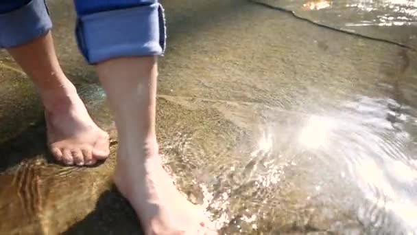 年轻女子赤脚在溪流中的水里泼洒和踢腿 水流缓慢 女士们在瀑布边享受与大自然同行的假期 暑假生活方式的概念 — 图库视频影像