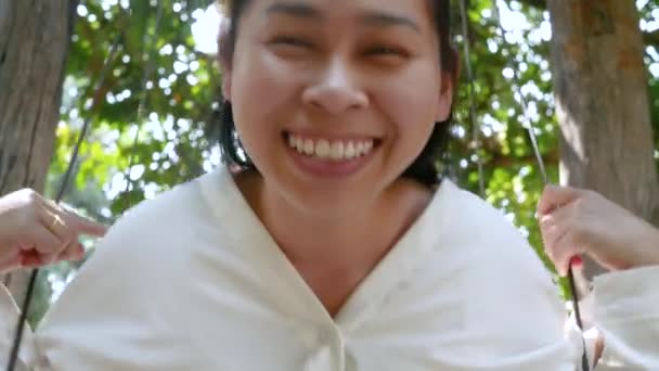 公園でスイングをしながら笑っている幸せな魅力的な若い女性 夏休みの生活の概念 — ストック動画