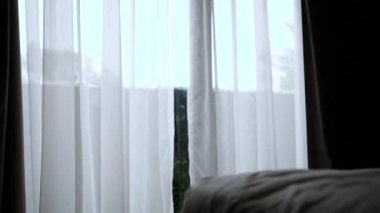 Güneş ışığı olan beyaz perdeli bir kapı ve sabahları rüzgar usulca eser..