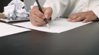 Genç stresli bir kadın küçük bir ofiste ya da işine kızgın bir şekilde masa başında oturuyor, hayal kırıklığına uğramış vücut ifadeleri ile buruşmuş belgeler ve etrafa kağıt parçaları saçıyor. Negatif insani duygu kavramı.
