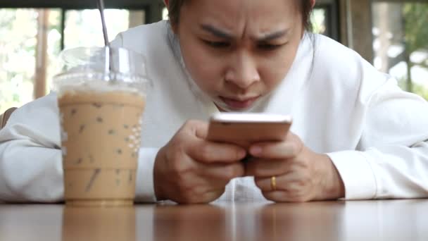 若い女性が座って 休日の間にカフェで激怒してスマートフォンでゲームをプレイ — ストック動画