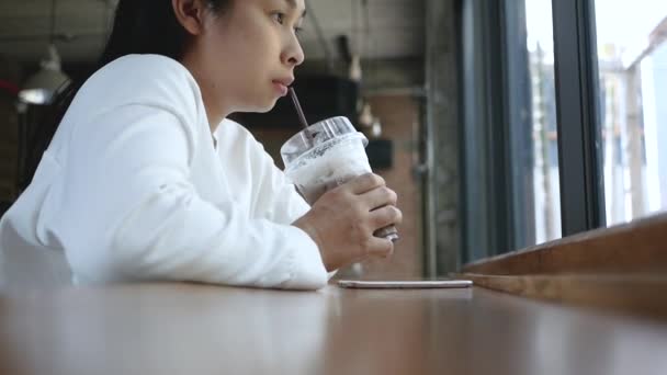 Atrakcyjna Kobieta Siedzi Patrzy Przez Okno Pijąc Mrożoną Kawę Słomką — Wideo stockowe