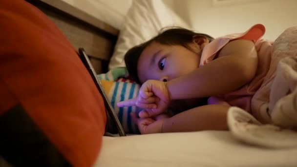 Kleines Asiatisches Kindermädchen Liegt Auf Dem Bett Und Schaut Spielen — Stockvideo