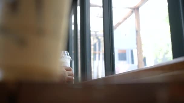 Atractiva Mujer Sentada Mirando Por Ventana Mientras Toma Café Helado — Vídeo de stock