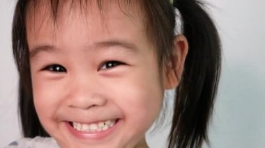 Mutlu Asyalı küçük kızın yüzünü kapatın dans ederek ve beyaz arka planda 