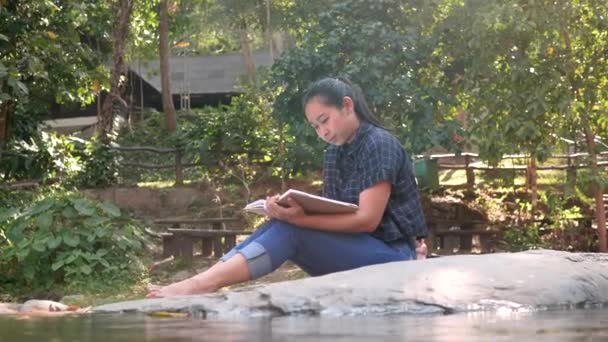 Atractiva Joven Asiática Sentada Leyendo Libro Sobre Rocas Con Agua — Vídeos de Stock