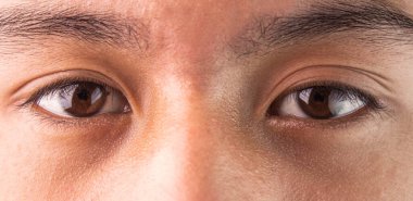 Doğrudan hedefe bakan Asyalı genç kahverengi gözlü adama yakın çekim. Sağlıklı yaşam konsepti.