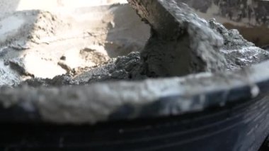 İnşaat işçisi veya sıva işçisi inşaat alanındaki plasttik pikapta çimento ve kumu karıştırmak için çapa kullanıyor. İnşaat konsepti.
