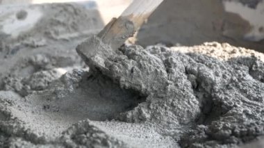 İnşaat işçisi veya sıva işçisi inşaat alanındaki plasttik pikapta çimento ve kumu karıştırmak için çapa kullanıyor. İnşaat konsepti.