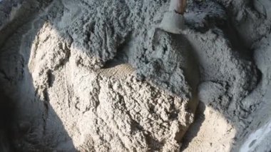 İnşaat işçisi veya sıva işçisi inşaat alanındaki plasttik pikapta çimento ve kumu karıştırmak için çapa kullanıyor. İnşaat konsepti.