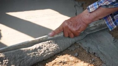 İnşaat işçisi veya sıva işçisi zemine beton döker ve pürüzsüz olması için beton zemini yerle bir eder. İnşaat konsepti.