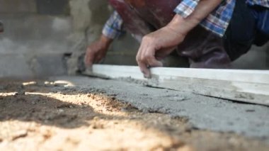 İnşaat işçisi veya sıva işçisi zemine beton döker ve pürüzsüz olması için beton zemini yerle bir eder. İnşaat konsepti.