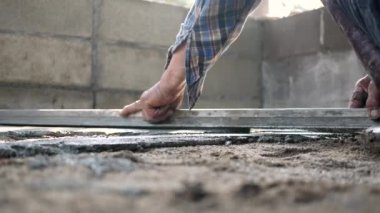 İnşaat işçisi veya sıva işçisi zemine beton döker ve pürüzsüz olması için beton zemini yerle bir eder. İnşaat konsepti.